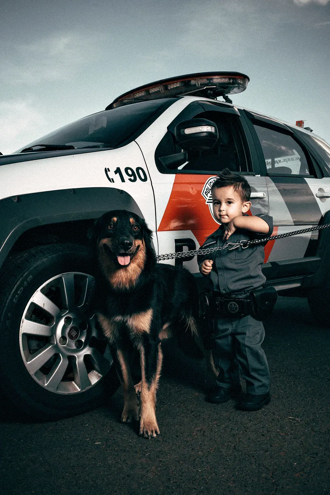 Rottweiler beside a police vehicle with a small child in uniform