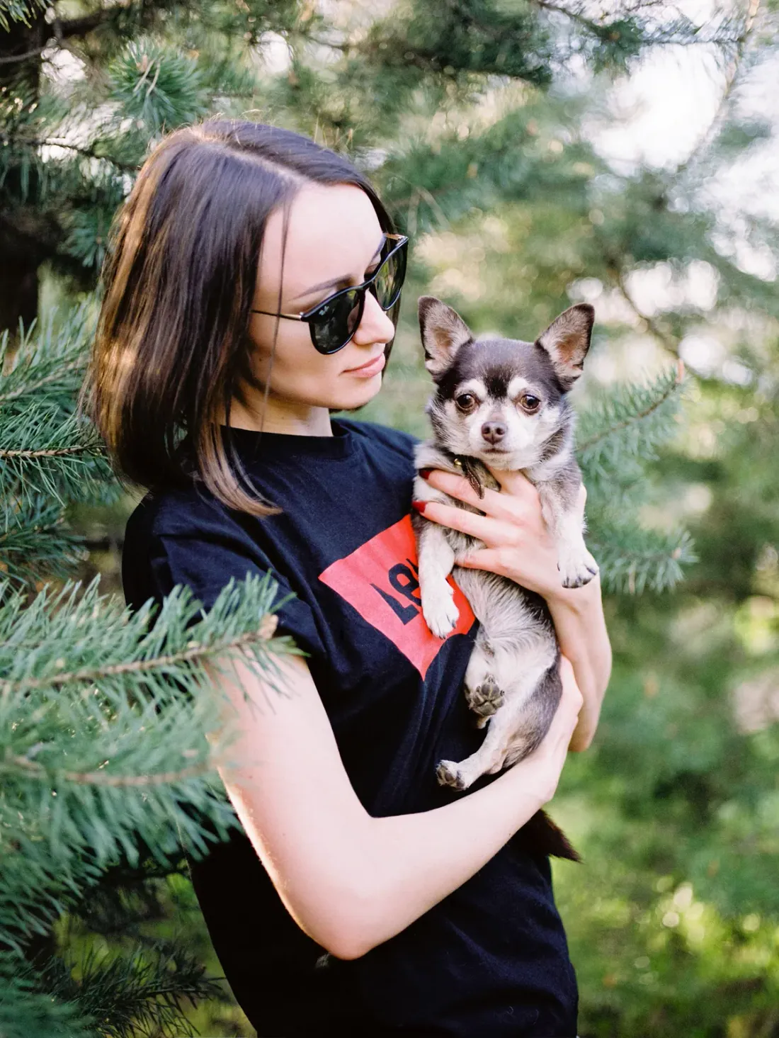 Woman holding a black and tan Chihuahua in her arms outdoors
